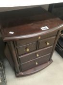 A dark wood stained small chest of drawers