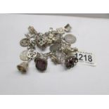 A silver charm bracelet with silver padlock and over 20 charms and coins (mostly unmarked),