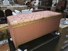 A pink wicker upholstered linen box