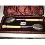 A cased pair of silver and ivory salad servers with carved depiction of frog and fly.
