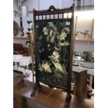 A wooden fire screen with a glazed embroidery of birds,