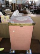 A pink painted woven wicker laundry basket