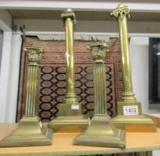 A pair of brass Corinthian column candlesticks and a pair of brass spring loaded candlesticks.