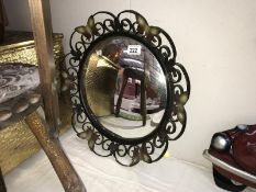A wrought iron framed convex mirror with butterfly decoration
