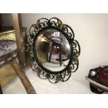 A wrought iron framed convex mirror with butterfly decoration