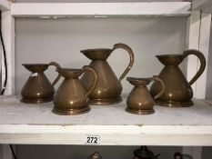 A set of 5 copper graduated jugs