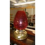 A large brass Sherwood's round wick oil lamp with ruby glass shade.