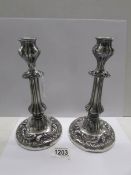 A pair of white metal candlesticks.