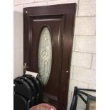 A heavy dark wood external door with oval glass insert