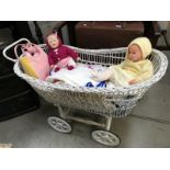 A wicker pram with spindle wheels and linen and 2 baby dolls