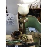 An ornate brass oil lamp with decorative lamp shade