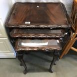 A nest of 3 carved wood tables