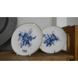 A pair of handpainted Meissen plates with blue floral designs and gold features.