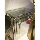 A glass topped brass effect nest of tables