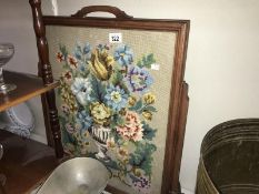 A dark wood stained fire screen with glazed tapestry panel