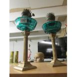A pair of Corinthian column oil lamp bases with green glass fonts.