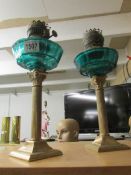A pair of Corinthian column oil lamp bases with green glass fonts.