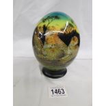 A decorated ostrich egg on stand signed Julie Morgan.