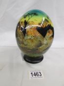 A decorated ostrich egg on stand signed Julie Morgan.