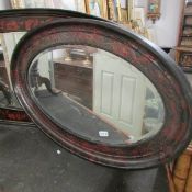 An oval bevel edged mirror in lacquered frame.