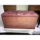 A pink button upholstered blanket box