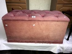 A pink button upholstered blanket box