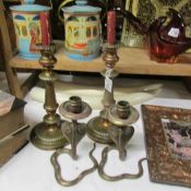 A pair of brass candlesticks and a pair of cobra candlesticks.