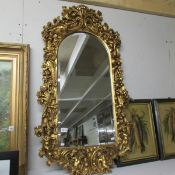 A gilt framed bevel edged mirror with arched top and cherub decoration.