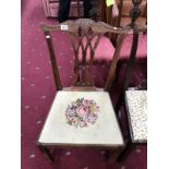 An ornately carved dining chair with floral patterned seat