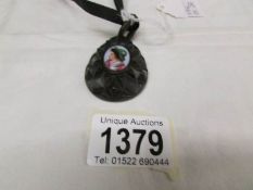 A 19th century carved Whitby jet pear shaped pendant with a porcelain portrait of a young boy on a