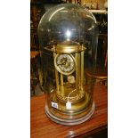 A brass clock with Palladian columns under a glass dome.