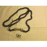 A black/navy pearl necklace with silver dragon fastening, 37" long.
