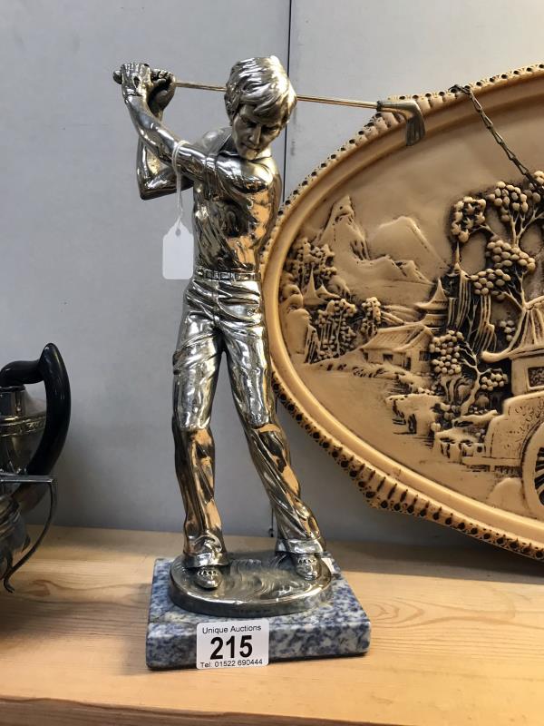 A silver plated figure of a golfer