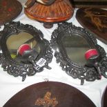 A pair of cast iron mirrors with candle sconces.