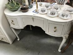 A kidney shaped dressing desk in white with gold trim