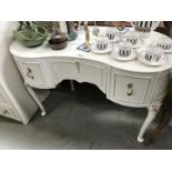 A kidney shaped dressing desk in white with gold trim