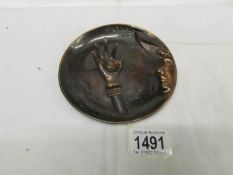 An old bronzed on pewter dish depicting a lady with dove in hand.
