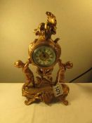 A gilt metal clock surmounted cherubs, needs attention.