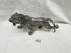 A white metal figure of a tiger.