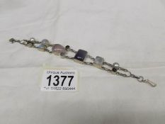 A multi gem set bracelet with garnet, pearl etc in silver.