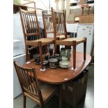 An oval extending table with 6 strut back woven seated dining chairs