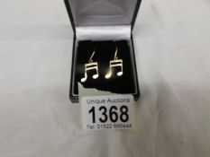 A pair of 9ct gold ear pendants fashioned as music semi quaver notes.