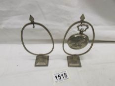A pocket watch and 2 pocket watch stands.