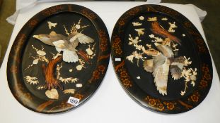 A pair of oval lacquered plaques with applied mother of pearl eagles.