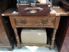 A carved wood side table with spindle legs and leg struts and one drawer