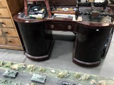 A curved kneehole desk with embossed dark green inlaid leather writing surface