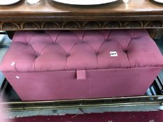 A pink button upholstered blanket box