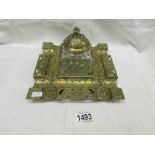 A decorative brass inkstand with angel detail and glass inkwell.