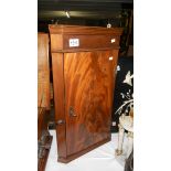 A small mahogany corner cupboard.