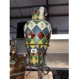 A colourful glazed amphora vase on a metal tripod stand